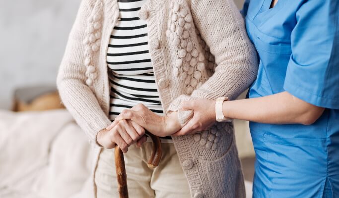 Elderly women being guided by nurse in care home