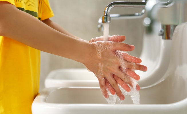 Young child washing their hands at school